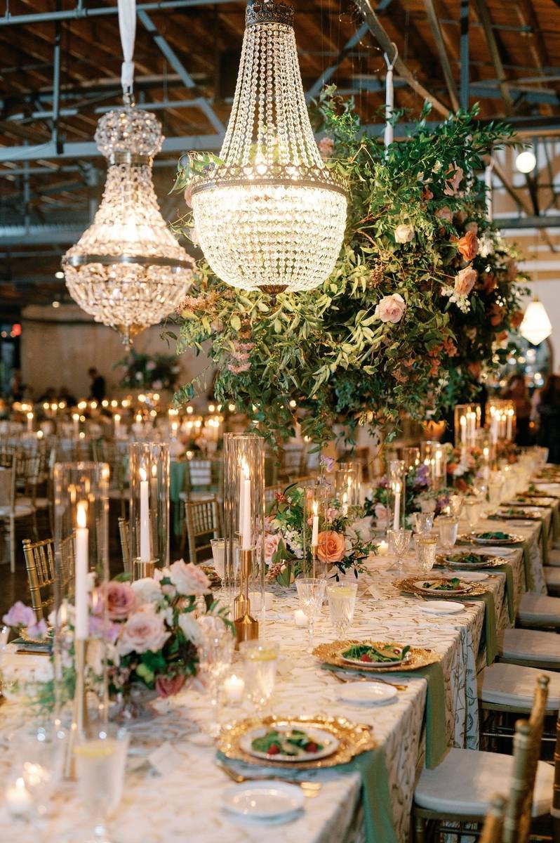 Crystal chandeliers and candlelight over a long reception table at a Nashville wedding